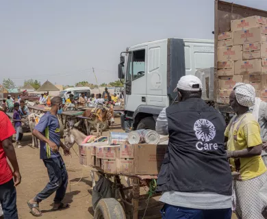 A food distribution scene in Kassala, Sudan, showing aid workers and locals gathering around a truck loaded with supplies, highlighting the hunger crisis in the country.